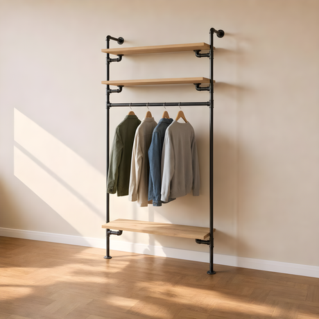 Étagère-penderie murale en tuyaux de plomberie noirs Ø 27 mm, tablettes en chêne clair et barre de penderie garnie de vêtements sur cintres